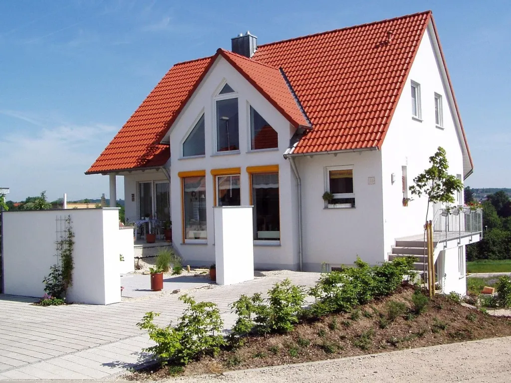 Nowoczesny dom jednorodzinny o minimalistycznej architekturze, prezentujący ofertę luksusowych apartamentów.
